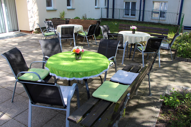 Die Terrasse unserer Einrichtung in Grünau. Mehrere Gartenmöbel stehen dort und der Tisch ist für das Kaffeetrinken gedeckt.