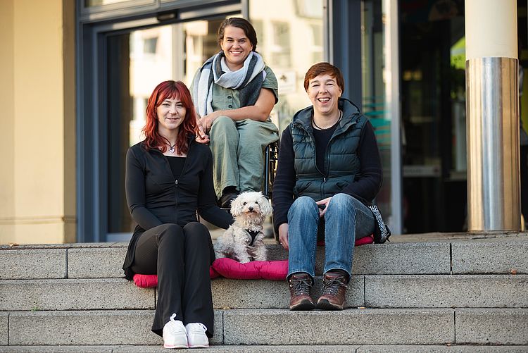 Mitarbeiter*innen des STZ sitzen auf der Treppe des Moritzhofs
