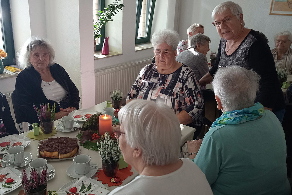 mehrere Seniorinnen sitzen an einer festlichen Kaffeetafel