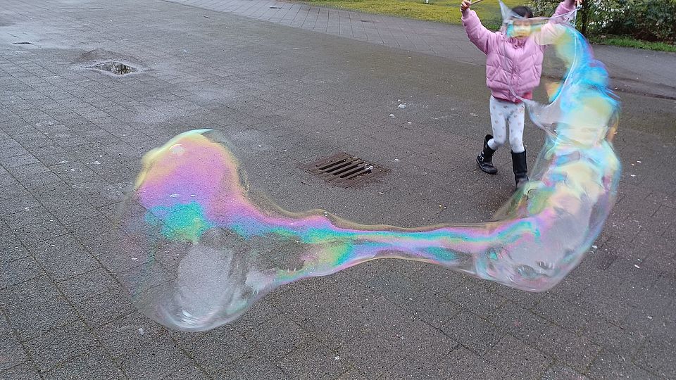 Kind macht riesen Seifenblasen im Freien