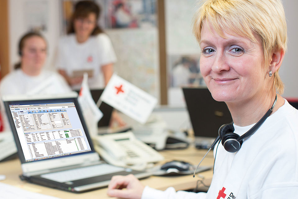 Frau mit Head Set sitzt an Laptop