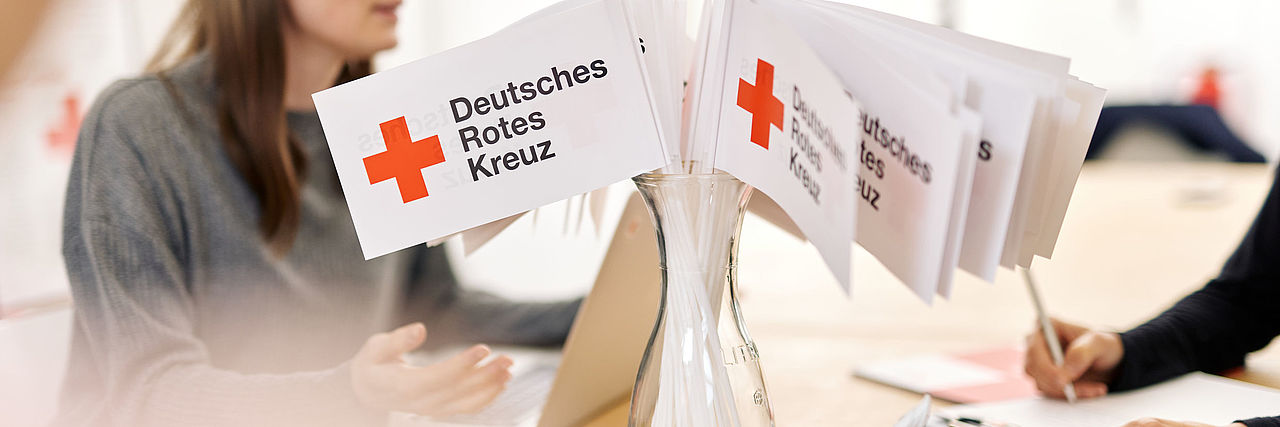 Gesprächsrunde am Tisch mit vilen DRK-Fähnchen