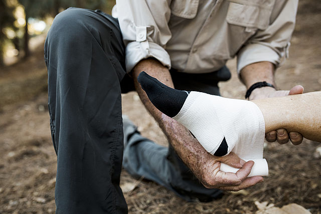 Elderly man bandaging his wifes ankle