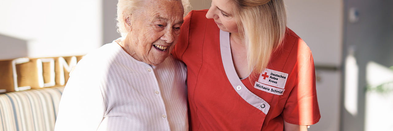 Pflegekraft stützt Seniorin