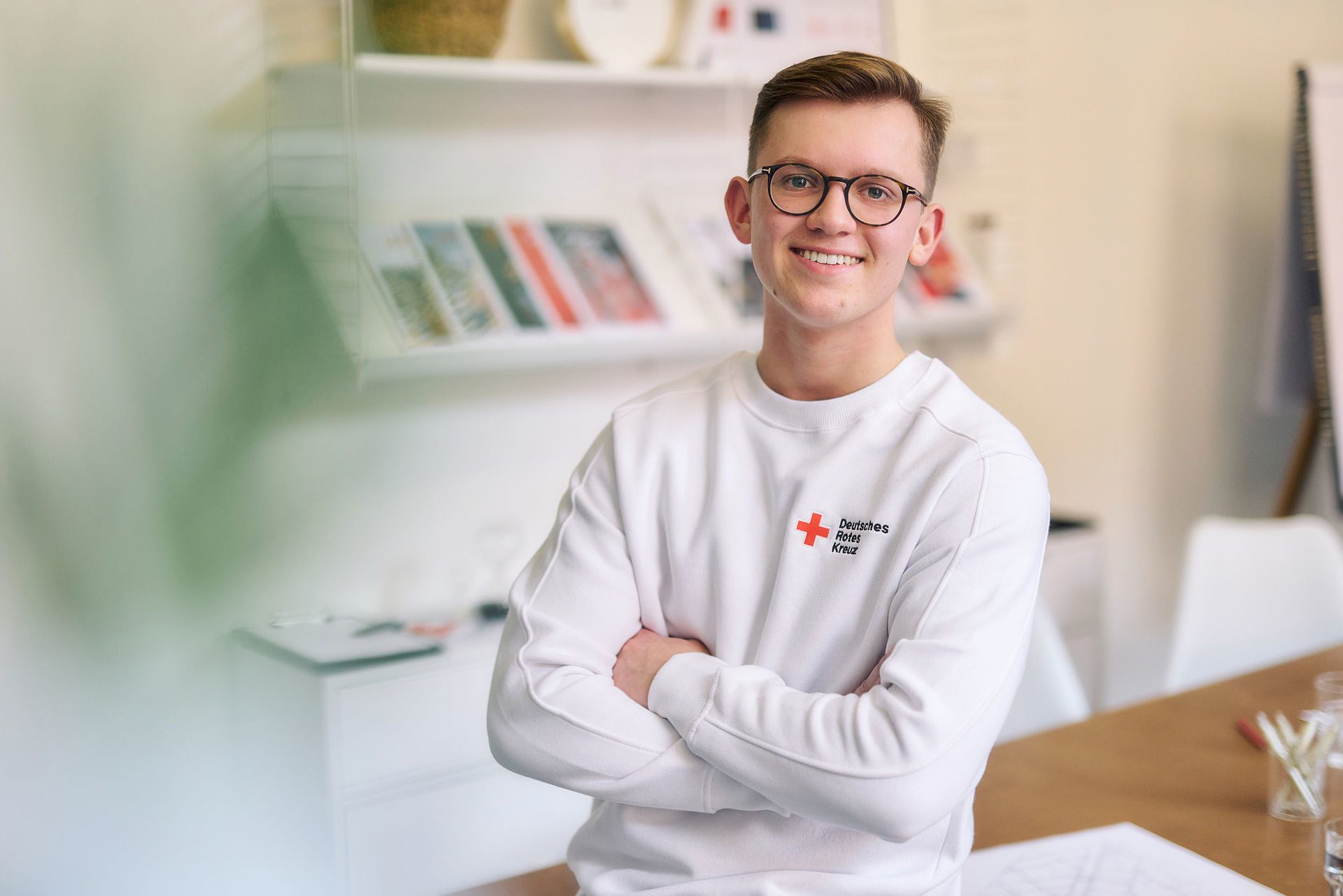 junger Mitarbeiter des DRK, er trägt ein weißes Sweatshirt mit DRK-Logo  - 22.10.2022