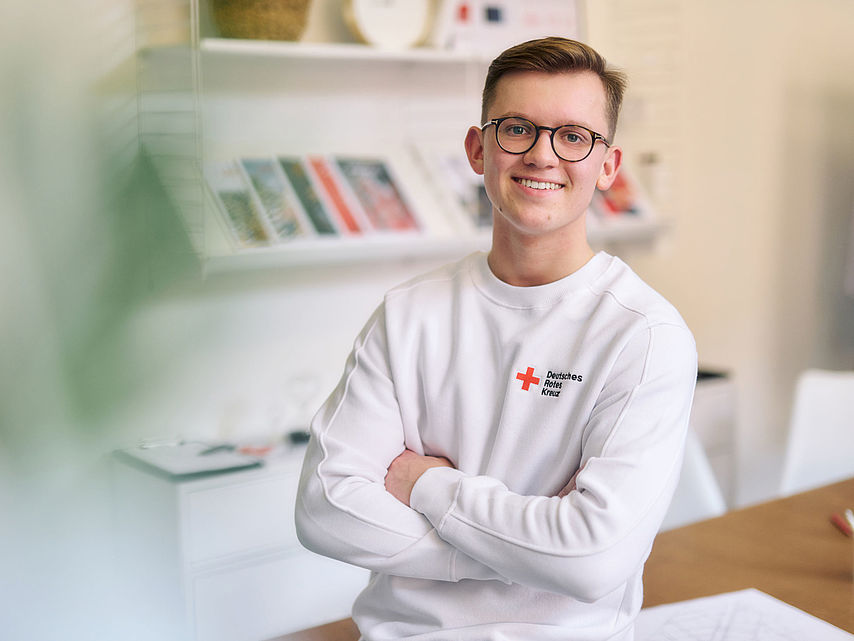 junger Mitarbeiter des DRK, er trägt ein weißes Sweatshirt mit DRK-Logo  - 22.10.2022