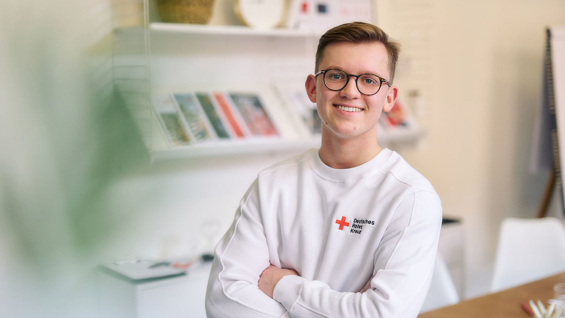 junger Mitarbeiter des DRK, er trägt ein weißes Sweatshirt mit DRK-Logo  - 22.10.2022