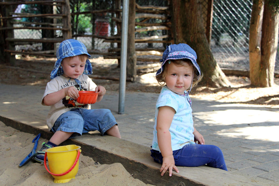 zwei Kinder sitzen auf dem Rand des Sandkastens