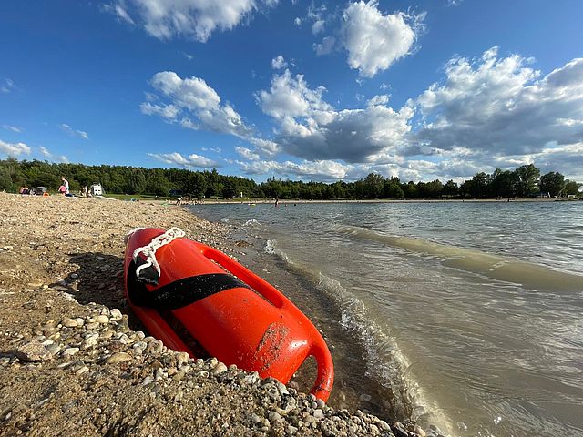 Rettungsboje liegt im Kies am Gewässerrand