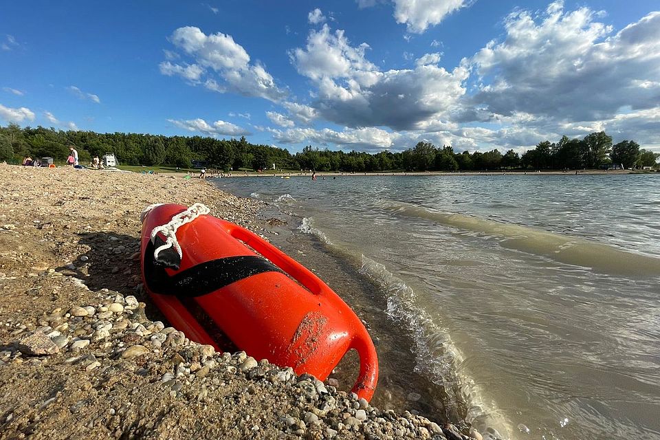 Rettungsboje liegt im Kies am Gewässerrand
