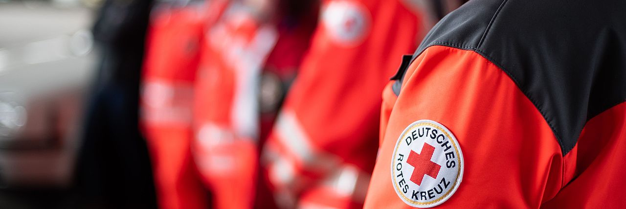 Menschen in DRK-Einsatzkleidung stehen hintereinander
