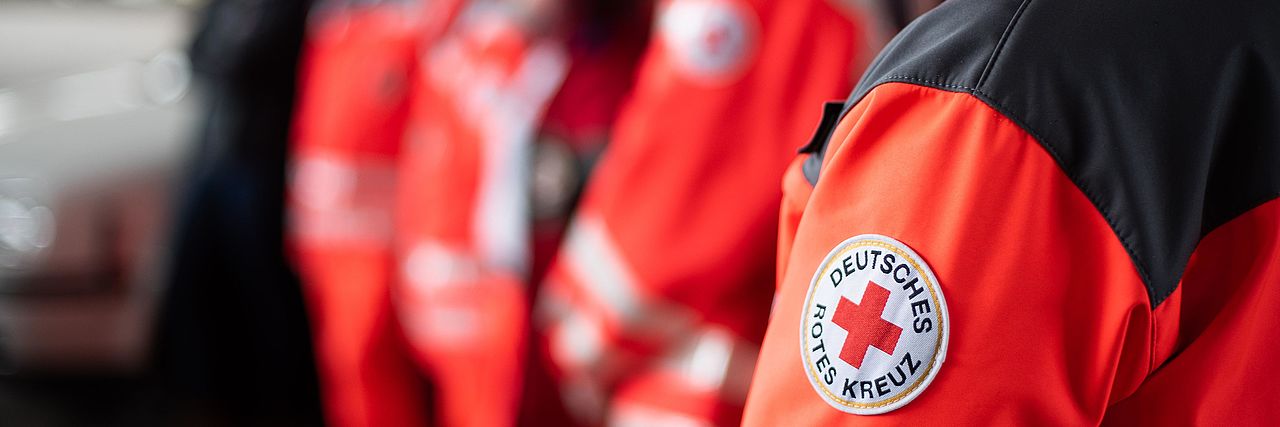 Menschen in DRK-Einsatzkleidung stehen hintereinander Menschen in DRK-Einsatzkleidung stehen hintereinander
