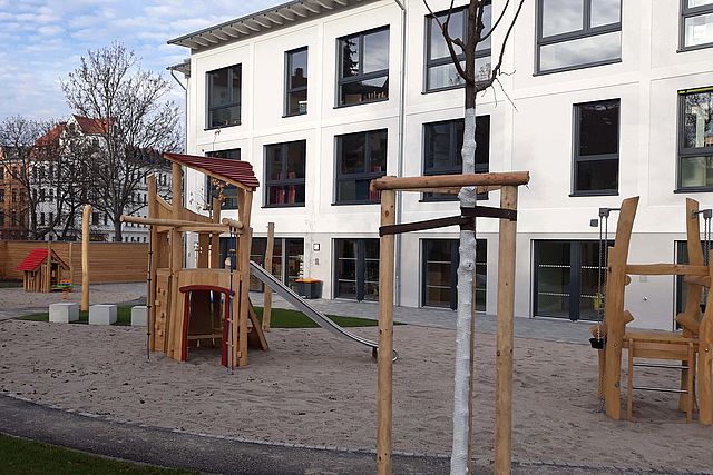 Kletter- und Rutschelement im Garten, Gebäude im Hintergrund