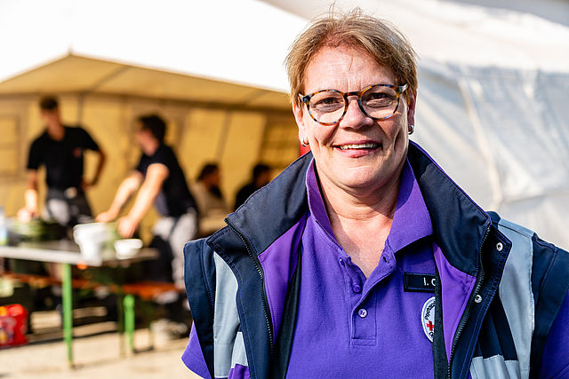 Helferin steht vor Verpflegungszelt