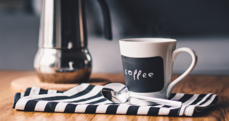 auf einer Tischplatte befinden sich Kaffeetasse, Löffel und Stoff