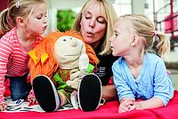 Kita-Erzieherin mit zwei Kindern beim Spielen