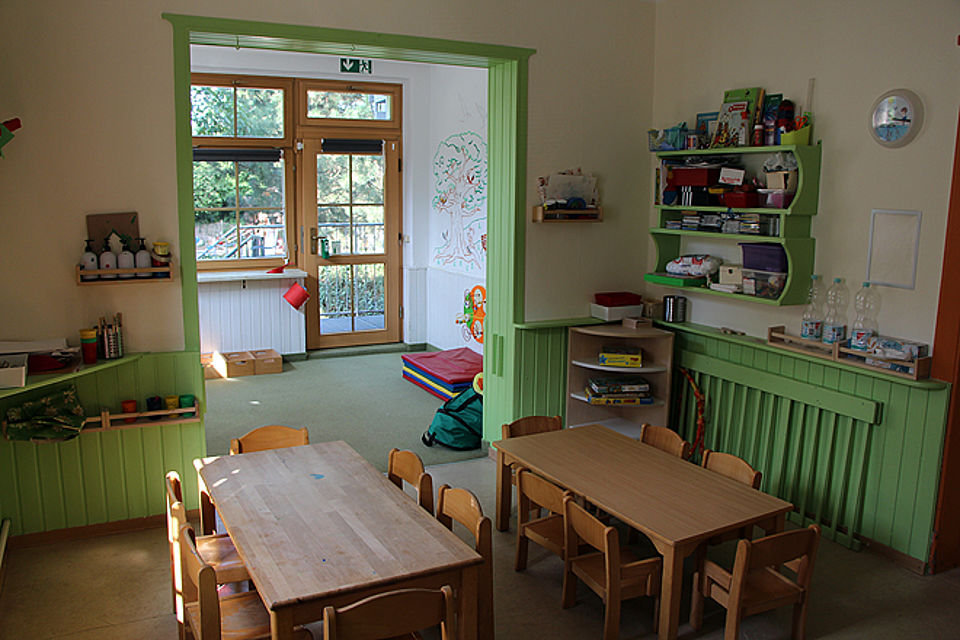 holzgetäfelter Raum mit Tischen und Stühlen für Kinder