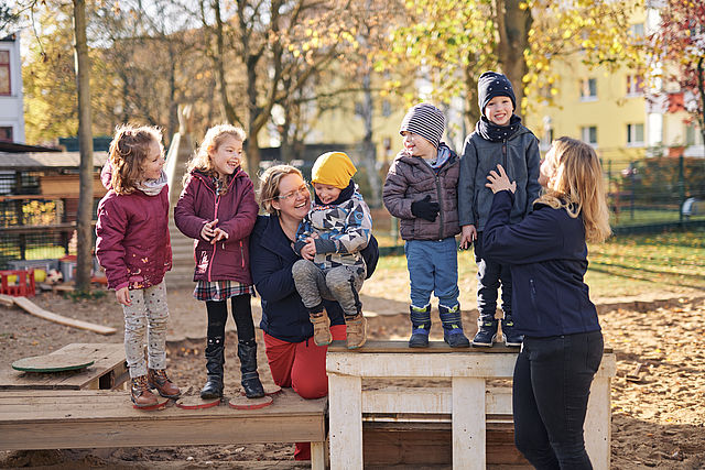 Erzieherinen und Kinder beim Spielen im Garten der KiTa