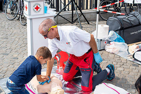 Erste-Hilfe-Ausbilder übt zusammen mit einem Kind Wiederbelebungsmaßnahmen