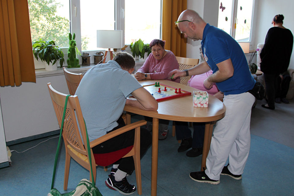 beeinträchtigte Personen spielen mit Pflegekraft Gesellschaftsspiel