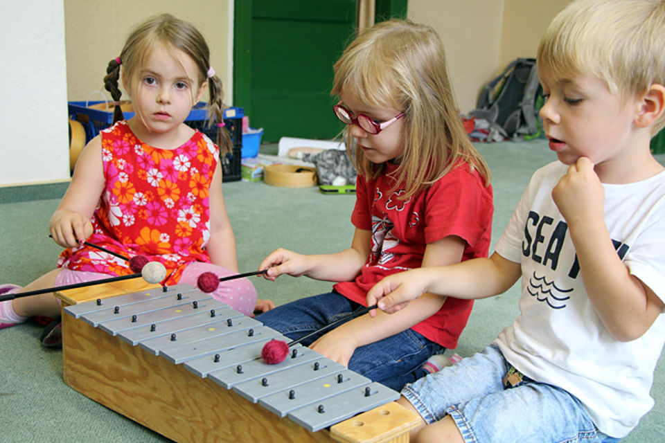 drei Kinder spielen auf einem Xylophon