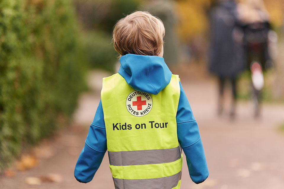 Kita-Kind trägt Leuchtweste mit DRK-Logo